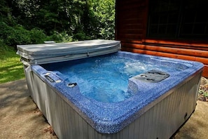 Ein Whirlpool mit Steinfassade, Bedienfeld und umlaufender Holzdielen-Terrasse.