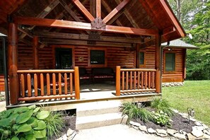 A wooden cabin with a porch, a small deck, and a stone pathway leading to the entrance. - Group Spacious Cabin with Hot-Tub and Picnic Areas in Ohio (Rockbridge)