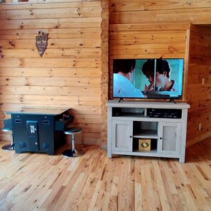 Ein Holzinnenraum mit einem Fernseher auf einem Schrank, einer Bar mit Hockern und einer Kommode mit einer kleinen Schachtel.