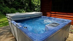 Ein Whirlpool mit Steinfassade, Bedienfeld und umlaufender Holzdielen-Terrasse.