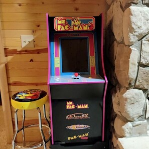 En ældre arkademaskine med påskriften 'Mr. Pac-Man', og en skammel stående ved siden af.