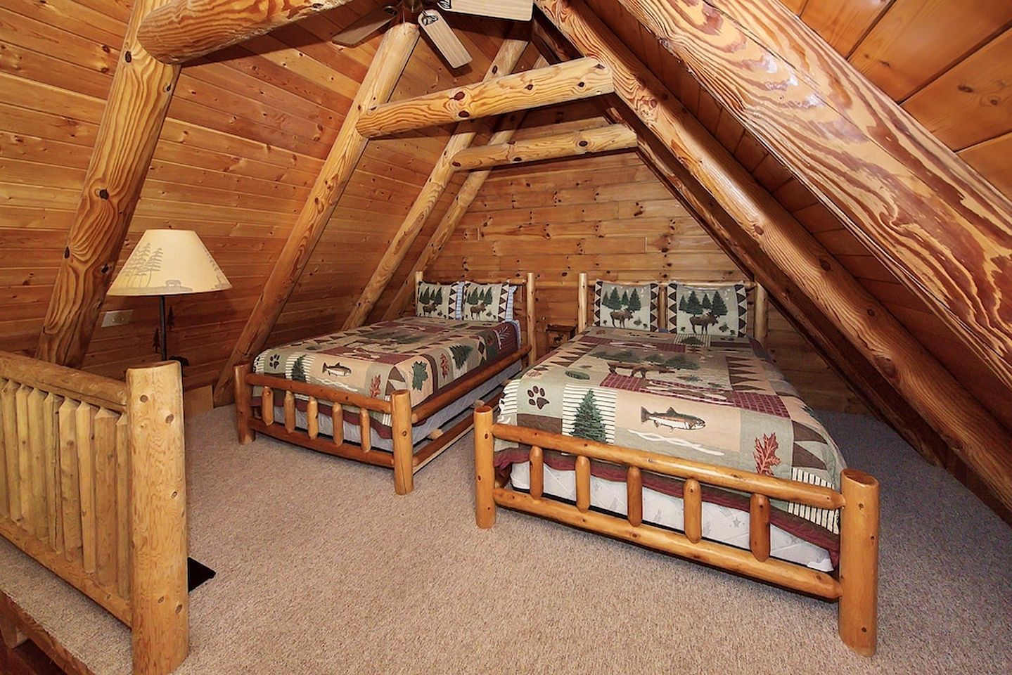 Une chambre mansardée chaleureuse avec deux lits en bois, une rambarde en bois et une lampe.