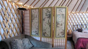 A room with a sofa, a bed, and a traditional screen with artwork. - Rustic Luxury: Riverfront Yurt Glamping in Claxton, Georgia (Claxton)
