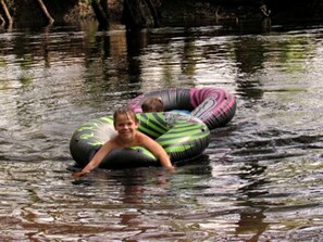 A person in a water body using a green and black inflatable tube.