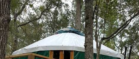 Una casetta sugli alberi con un patio in legno e una zona notte riparata.