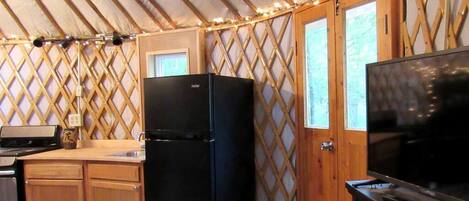 A compact kitchen with a refrigerator, a stove, and a television.