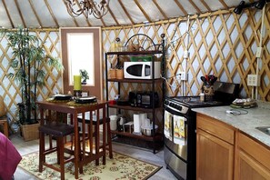 A compact kitchen with a stove, microwave, and a small dining area with chairs.