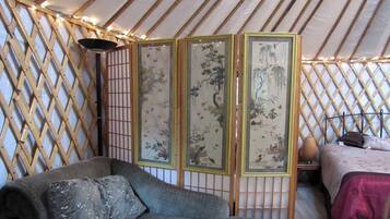 A room with a sofa, a bed, and a traditional Chinese screen with artwork.