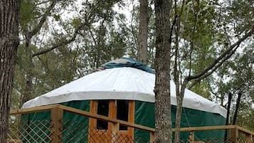 Une cabane dans les arbres dotée d’une terrasse en bois et d’un espace de couchage abrité.