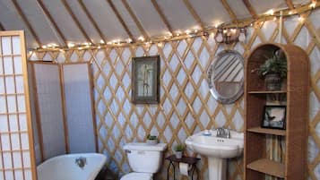 Une salle de bain avec une baignoire, des toilettes, un lavabo et un mur en treillis décoré de guirlandes lumineuses.