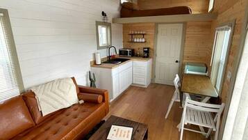 A compact living space with a kitchenette, a sofa, a coffee table, and a dining area.