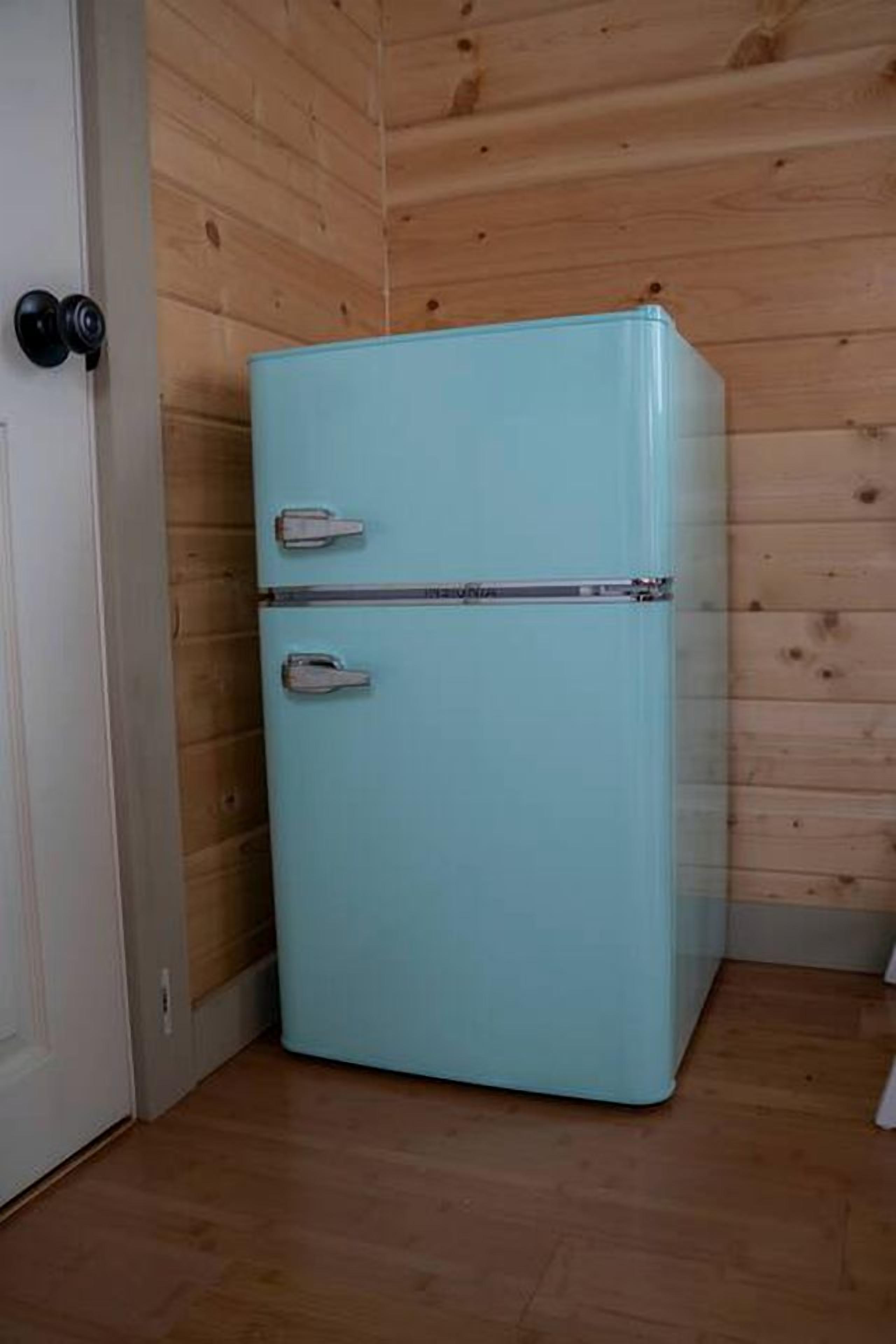 A light blue refrigerator in a room with wooden walls and a wooden floor.