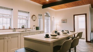 A kitchen with a central island, white cabinetry, and a wooden ceiling. - Spacious Strandhill House with Knocknarea Views (Strandhill)