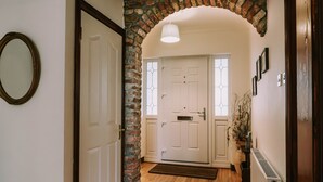 A hallway with a wooden floor, a white door, a brick archway, and a radiator. - Spacious Strandhill House with Knocknarea Views (Strandhill)