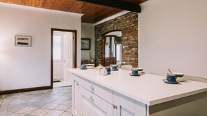 A kitchen with a white countertop, wooden ceiling beams, a stone wall, and a door leading to another room. - Spacious Strandhill House with Knocknarea Views (Strandhill)
