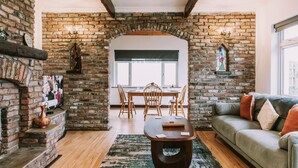 A cozy living room with a brick fireplace, a wooden dining table with chairs, and a green sofa. - Spacious Strandhill House with Knocknarea Views (Strandhill)