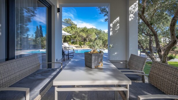 A modern outdoor seating area with a pool view, featuring a table and chairs, a potted plant, and a clear sky. - Villa Karla with pool&sea view by Villas Guide (Banjol)