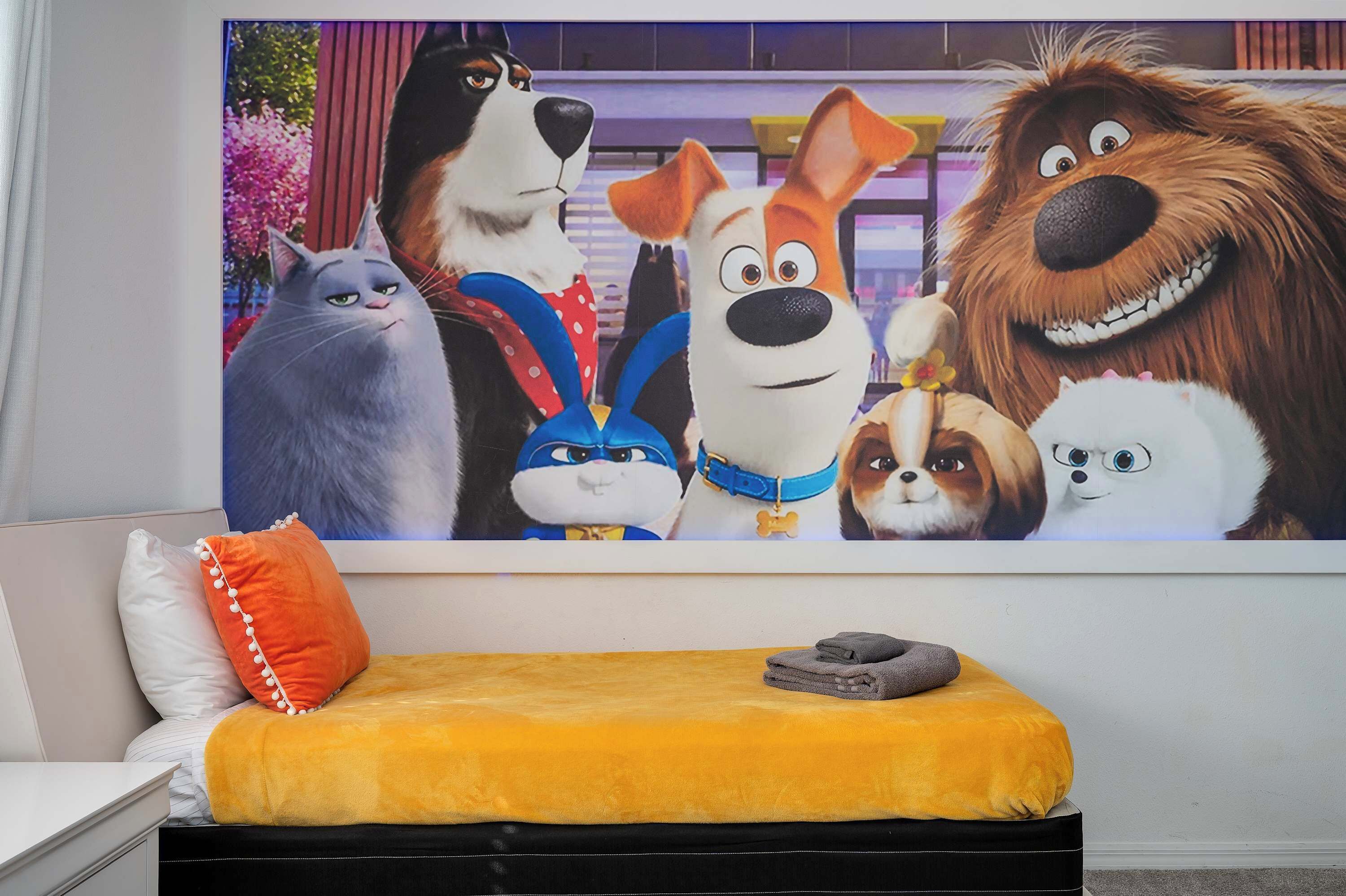 Un dormitorio con cama, almohadas, una colcha y un mural de personajes animados.