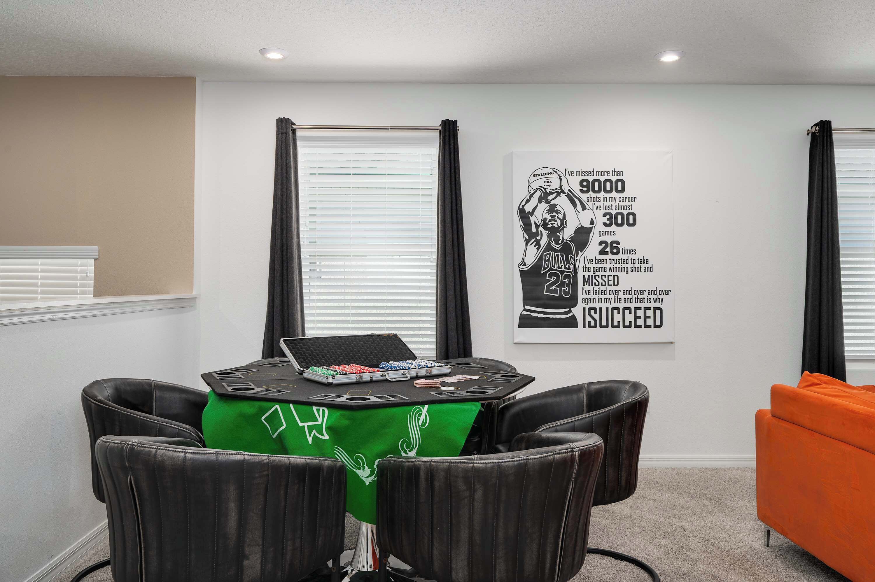 Une pièce avec une table préparée pour une partie de poker, une nappe verte et une affiche motivante accrochée au mur.