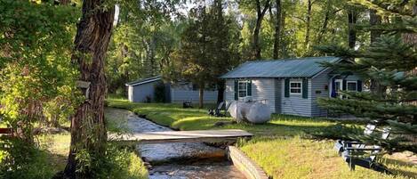 A rustic cabin with a small stream running through a garden.