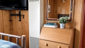 A wooden room with a bed, a dresser, a television, and a mirror.