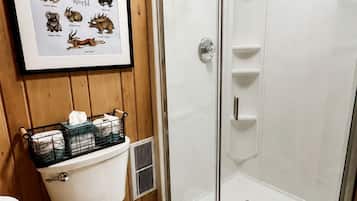 Een badkamer met een toilet, een douche en een ingelijst beeld van jackalopen.