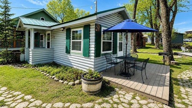 A log cabin with a porch, outdoor seating, and a garden.