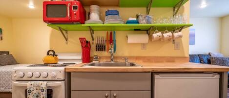 A compact kitchen with a stove, microwave, and a sink.