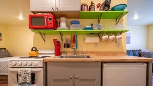 Una cocina compacta con estufa, microondas y lavamanos.