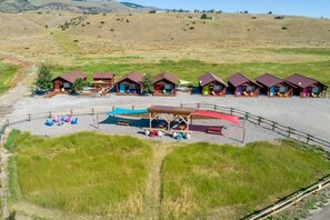 Un camping con varias cabañas, una zona de estar techada y un sendero de tierra.