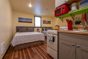 A compact room with a bed, a kitchenette, a stove, and a microwave. - Cozy Tiny Cabin with Breathtaking Emigrant Peak Views for an Amazing Escape in Montana (Emigrant)