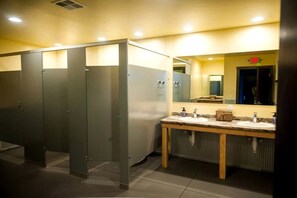 A public restroom with multiple stalls, a sink area, and a mirror.
