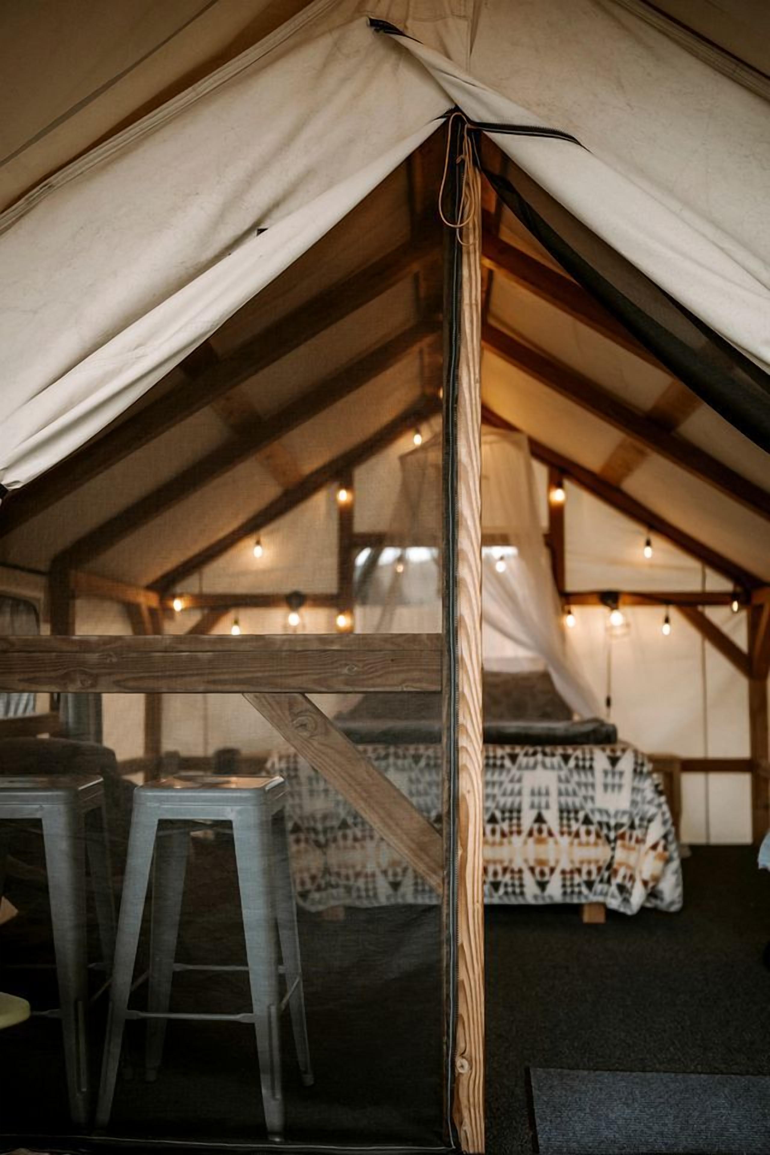 Ein Zelt mit Bett, Tisch und Hocker im Inneren.