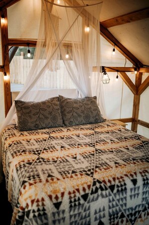 A bed with a patterned bedspread, a canopy, and a view of the outside.