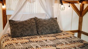 A bed with a patterned bedspread, a canopy, and a view of the outside.