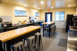 A kitchen with a wooden counter, stools, a refrigerator, and a stove.