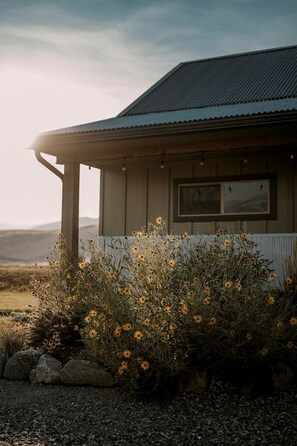 A building with a corrugated metal roof, a window, and a porch area with a white railing.