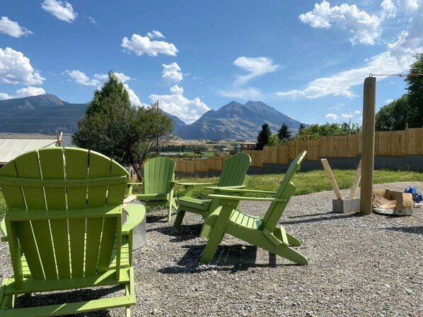 Outdoor seating with chairs and tables, a wooden fence, and a mountain backdrop.