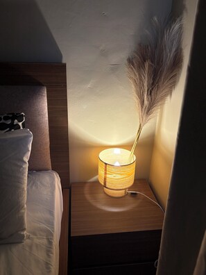 A bedside table with a lamp, a pillow, and a decorative feather. - Charming 2-bedroom apartment with AC in Kasoa (Kasoa)