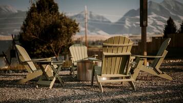 A row of Adirondack chairs facing a mountain view.