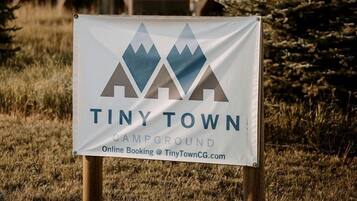 A sign for Tiny Town Campground with a mountain logo, indicating a nature-oriented setting.