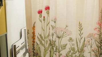 A shower curtain with a floral pattern, a towel rack, and a white tiled wall.