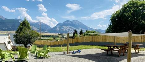 A patio area with green chairs, a picnic table, and a view of mountains.