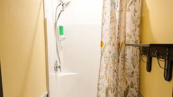 A shower with a floral curtain, a handheld showerhead, and a towel rack.