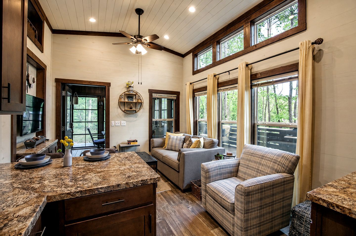 A spacious living area with a large window, a ceiling fan, and a cozy seating arrangement.