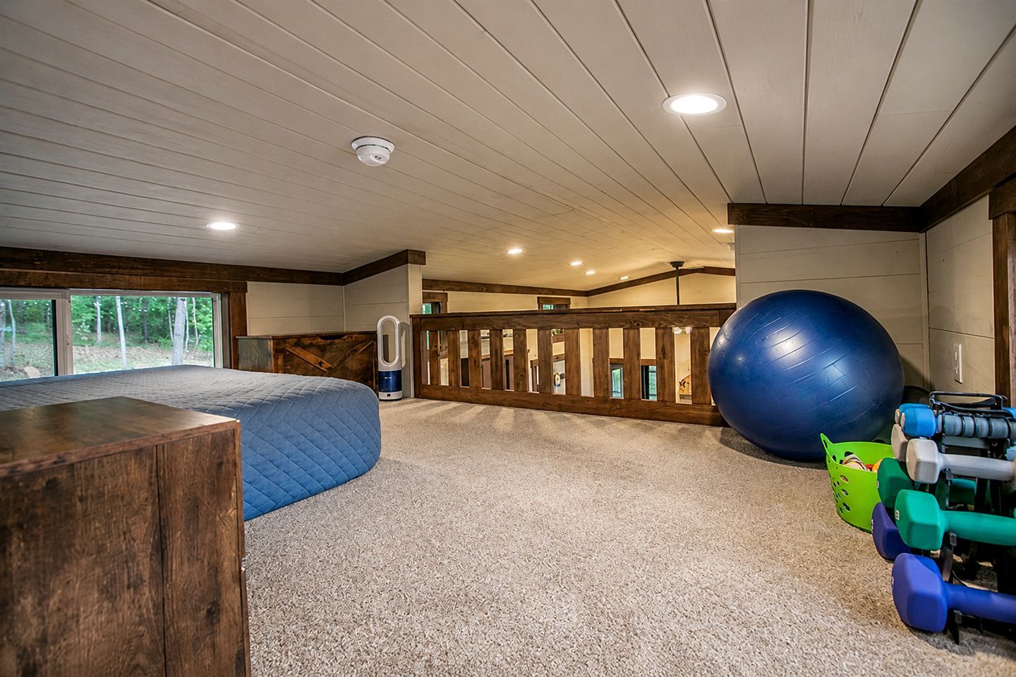 Una habitación amplia con una pelota de ejercicios grande, un banco de madera y una cafetera.
