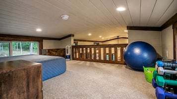 Una habitación amplia con una pelota de ejercicios grande, un banco de madera y una cafetera.