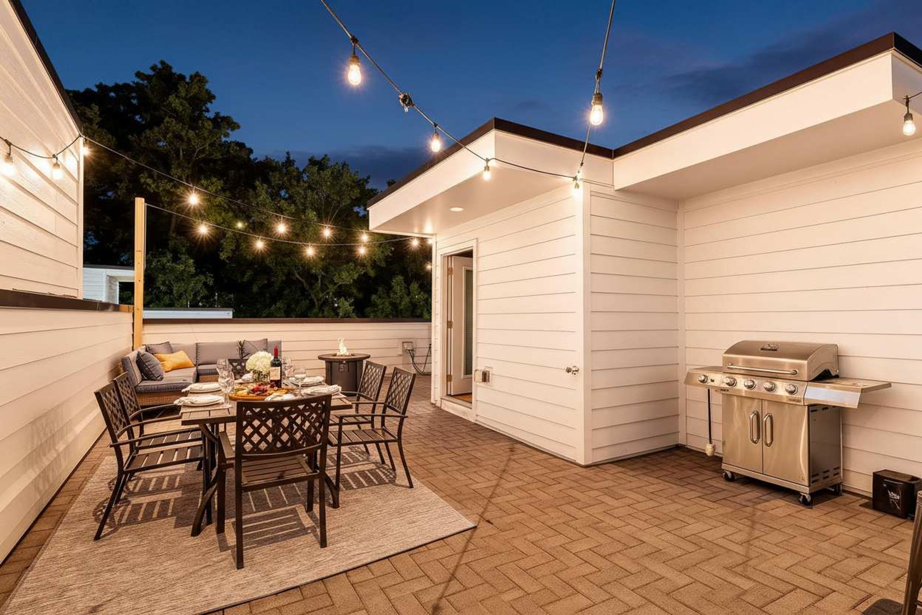 Une terrasse extérieure avec une table à manger, des chaises et un barbecue.