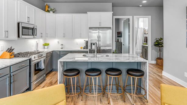 A modern kitchen with white cabinets, stainless steel appliances, and a central island with bar stools. - Grill Fire Pit Views Near Downtown Nashville (Nashville)