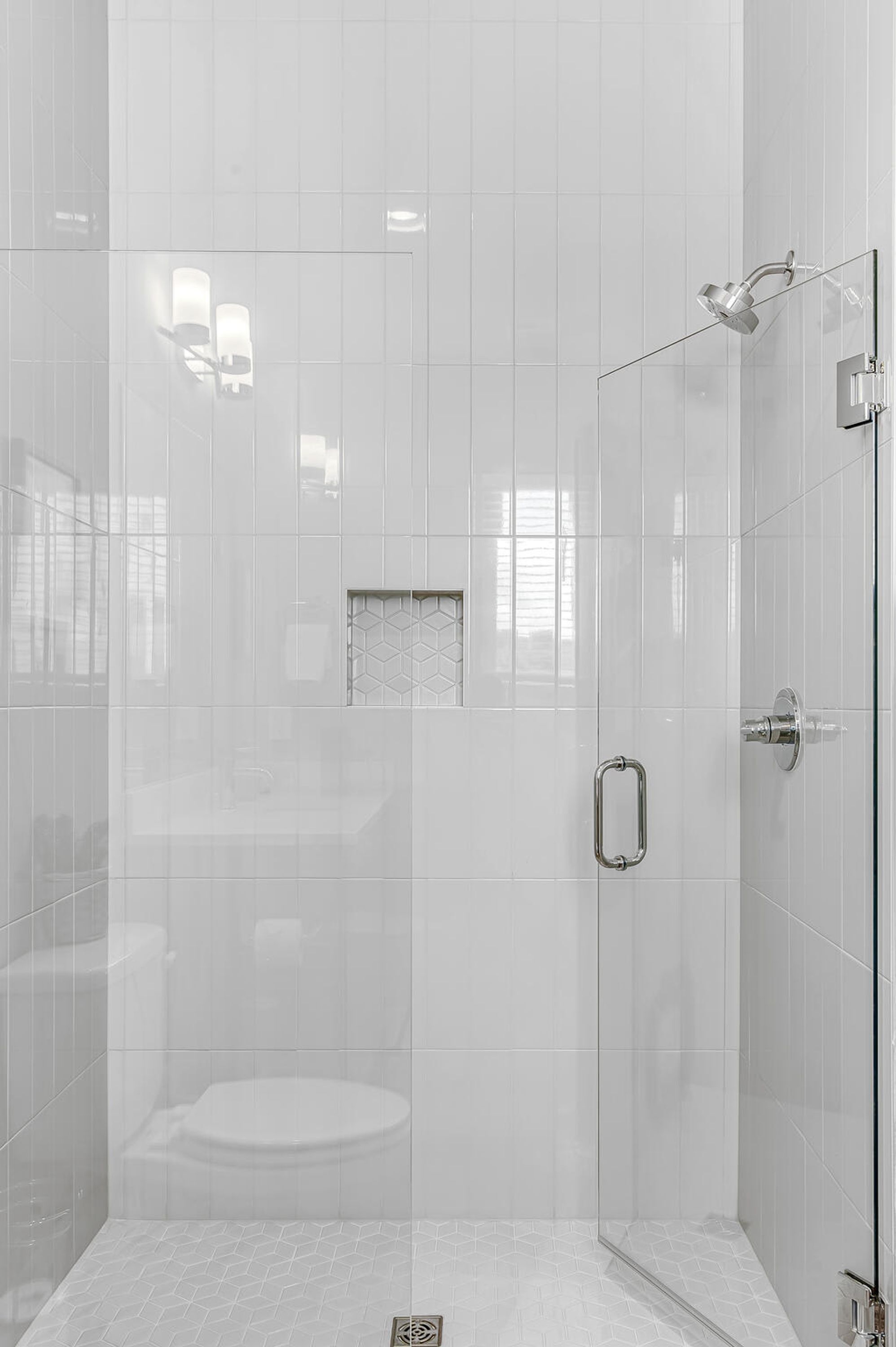 Een moderne badkamer met een douchecabine van glas, een toilet en een klein raam.